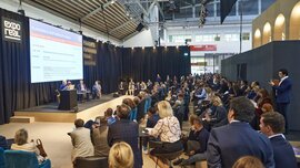 Das Planning & Partnership Forum auf der EXPO REAL mit fünf Rednern im Dialog auf der Bühne und zahlreichen Besuchern, die zuhören.