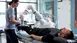 A therapist operates a robotic arm and helps a patient lying on a treatment table in a medical facility.