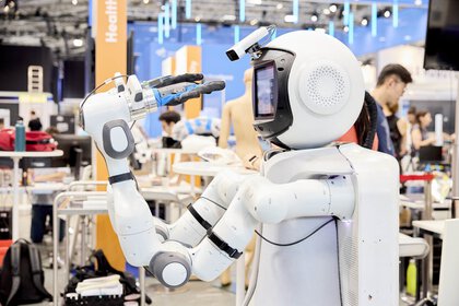 Humanoider Roboter mit Greifarmen auf einer Messe.