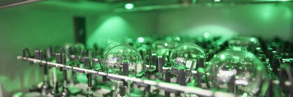 Close-up: Round-bottom flasks are turned upside down in a green-lit dishwasher for laboratory utensils.