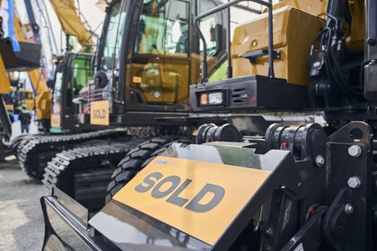 Baumaschine mit „SOLD“-Schild im Vordergrund, weitere verkaufte Bagger im Hintergrund.