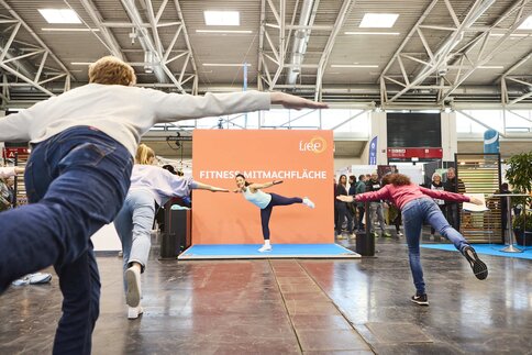 Trainerin leitet eine Fitness-Session auf der Mitmachfläche der Messe 