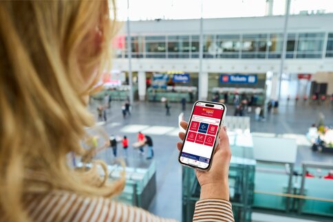 Frau hält ein Smartphone in den Händen auf dem die App der transport logistic geöffnet ist