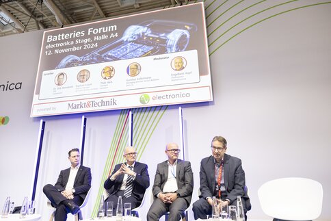 Four men sit in a panel discussion on the stage of the Batteries Forum in Hall A4 at electronica.