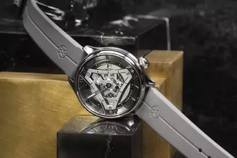 Eine silberne Uhr mit geometrischem Zifferblatt und grauem Armband, platziert auf einer reflektierenden Oberfläche.