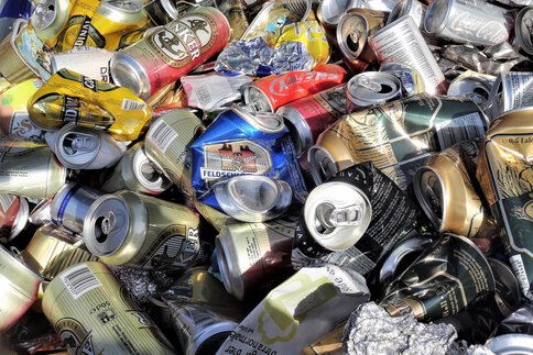 Large pile of crushed and empty aluminum beverage cans, some with visible brand logos, collected for recycling.
