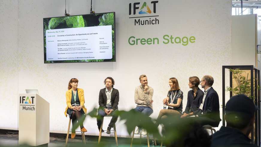 Podiumsdiskussion auf der Green Stage der IFAT Munich mit sechs Personen vor einer Leinwand.