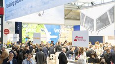 Numerous visitors to transport logistic bustle around various exhibition stands. In the background you can see some signs about air transportation.