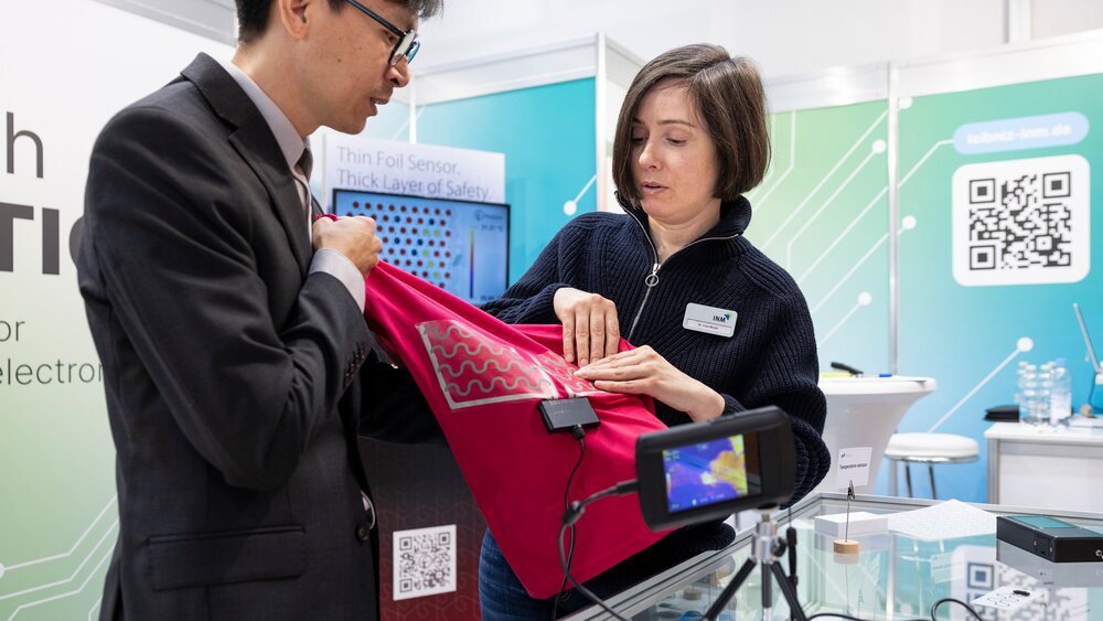 Demonstration of a textile-integrated heating element with a thermal camera at a LOPEC booth