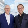 Die CEO Doppelspitze der Messe München ist auf einem gut beleuchteten Bild mit einem Gebäude im Hintergrund abgebildet zu sehen.