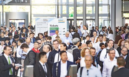 Crowd in the entrance hall. In focus is the signpost to the ticket booths.