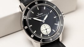 Close-up view of a wristwatch with a black dial featuring a separate dial for the second hand and a black bezel.