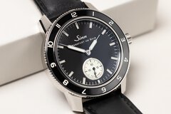 Close-up view of a wristwatch with a black dial featuring a separate dial for the second hand and a black bezel.