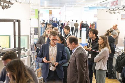 People interact at the busy LOPEC trade fair, surrounded by stands and exhibitions.