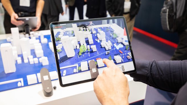 Person, die ein Tablet verwendet, auf dem eine 3D-Augmented-Reality-Karte einer Stadt mit verschiedenen Gebäuden angezeigt wird.