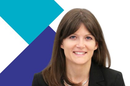 Lächelnde Frau mit langen braunen Haaren und schwarzem Blazer vor blauen und blaugrünen geometrischen Formen.