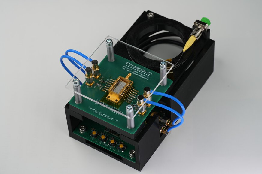 Photonik-Demonstrator von PhoenixD mit optischer Chipintegration, grüner Platine und blauen Anschlussleitungen