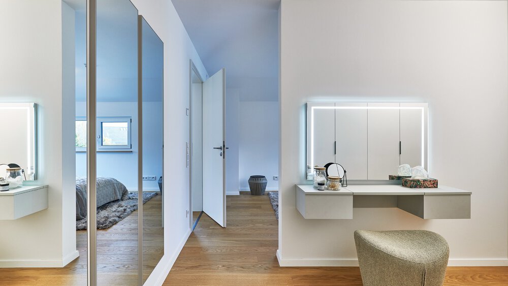 Modernes Schlafzimmer mit großen Spiegeln, Holzboden und einer Glastrennwand mit Blick auf das Bett.