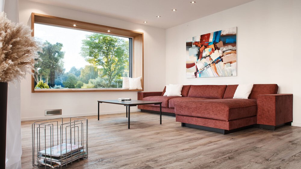 Modernes Wohnzimmer mit rotem Sektionssofa, abstrakter Kunst, großem Fenster und Holzfußboden.