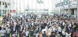 A large crowd flows through the exhibition entrance hall.