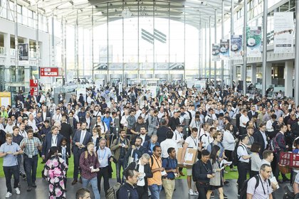 Eine große Menschenmenge strömt durch die Messe-Eingangshalle.