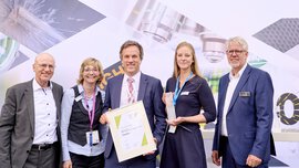 Drei Personen mit Auszeichnungen vom Innovation Award 2023, flankiert von zwei Männern in Anzügen.