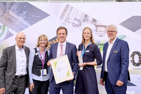 Three people with awards from the Innovation Award 2023, flanked by two men in suits.