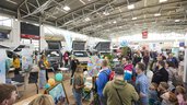 Eine menschengefüllte Messehalle zum Thema Caravan und Camping. Im Hintergrund sich verschiedene Camper-Vans.