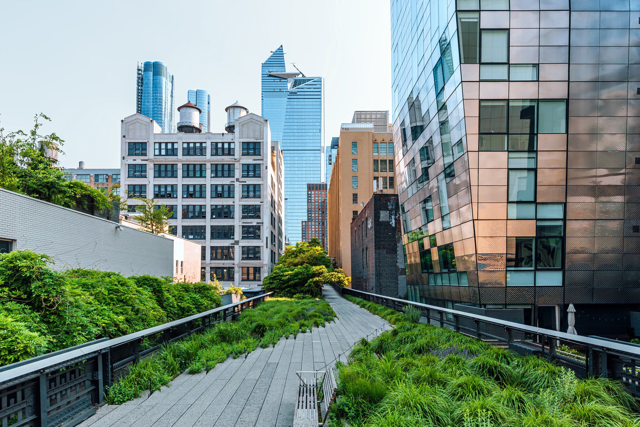 A green-lined pedestrian path leads between several modern high-rise buildings into the distance.