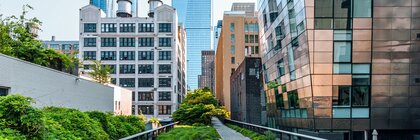 A green-lined pedestrian path leads between several modern high-rise buildings into the distance.