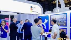 Besucher an einem Stand der transport logistic CHINA diskutieren an Stehtischen. Darüber ist ein Banner mit dem Slogan 