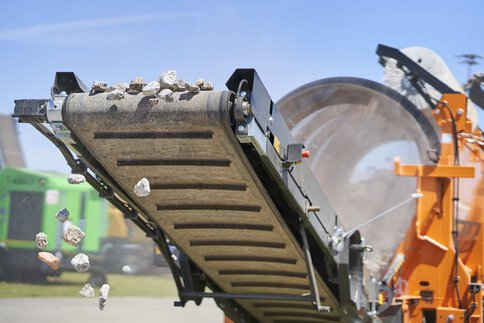 Close-up of a conveyor belt on the open-air site, with stones falling from the front.