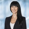 Frau mit langen, schwarzen Haaren und Pony lächelt in die Kamera.