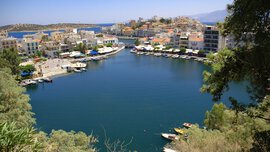 Coastal town with colorful buildings on a quiet bay, docked boats, and lots of greenery in the foreground.