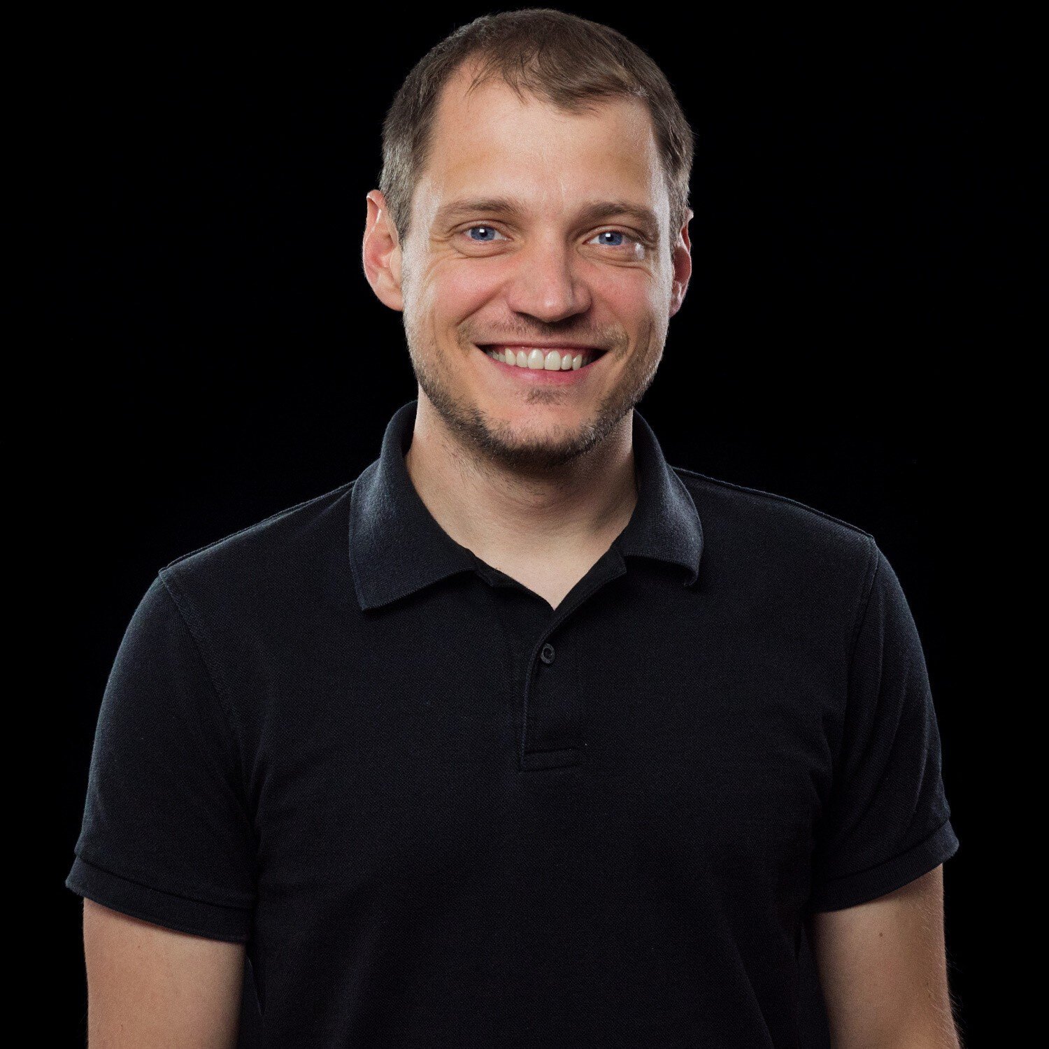 Porträt eines lächelnden Mannes vor schwarzem Hintergrund