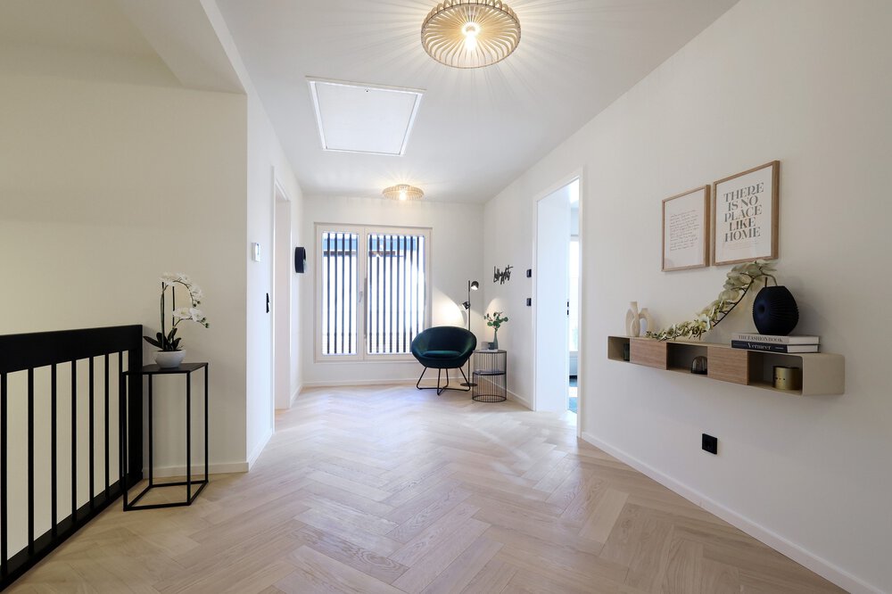 Heller, moderner Flur mit Holzboden, einem grünen Stuhl, Wanddekor und minimalistischen Regalen.