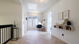 Heller, moderner Flur mit Holzboden, einem grünen Stuhl, Wanddekor und minimalistischen Regalen.