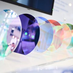 Close-up of several color-coated optical discs at a trade fair stand for laser and photonics technologies.