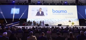 Large event with an audience in front of a stage featuring the 
