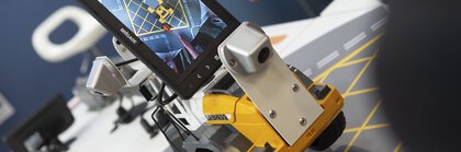 One person controls a small robot with wheels and a screen that shows a map.