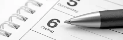 Close-up of a spiral calendar with a ballpoint pen on it.