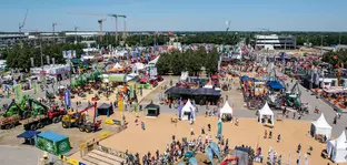 Aerial view of the open-air grounds of Messe München during INTERFORST. Numerous people visit colourful stands, tents and forestry machinery.