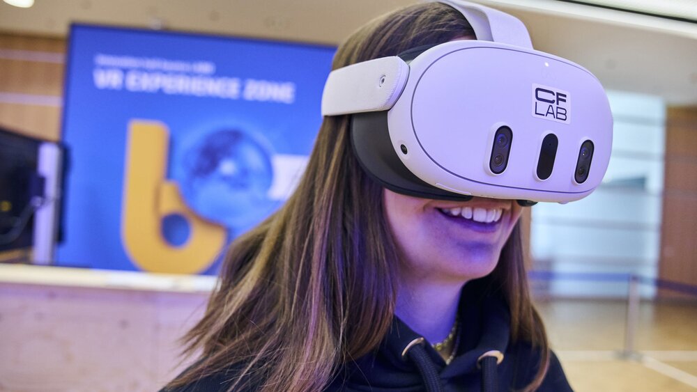 Messebesucherin erlebt eine VR-Anwendung mit VR-Brille in der Experience Zone der bauma.