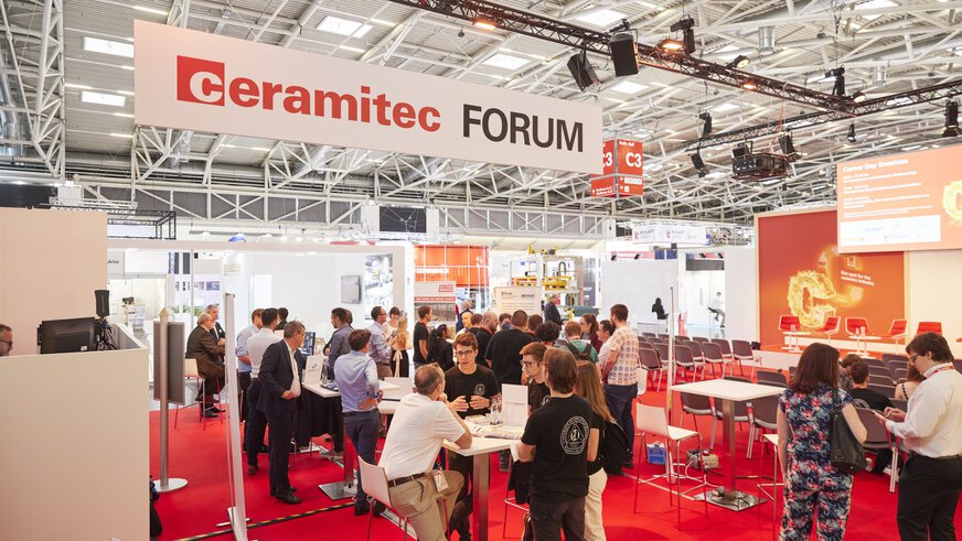 A busy exhibition hall with people standing under a sign reading 