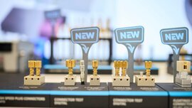 Nahansicht von mehreren, unterschiedlich gebauten weiß-goldenen Connectoren, auf die mehrere Schilder mit dem Aufdruck „NEW“ deuten.