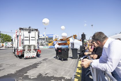A presentation of a refuse collection vehicle takes place on the open-air site in front of an audience.