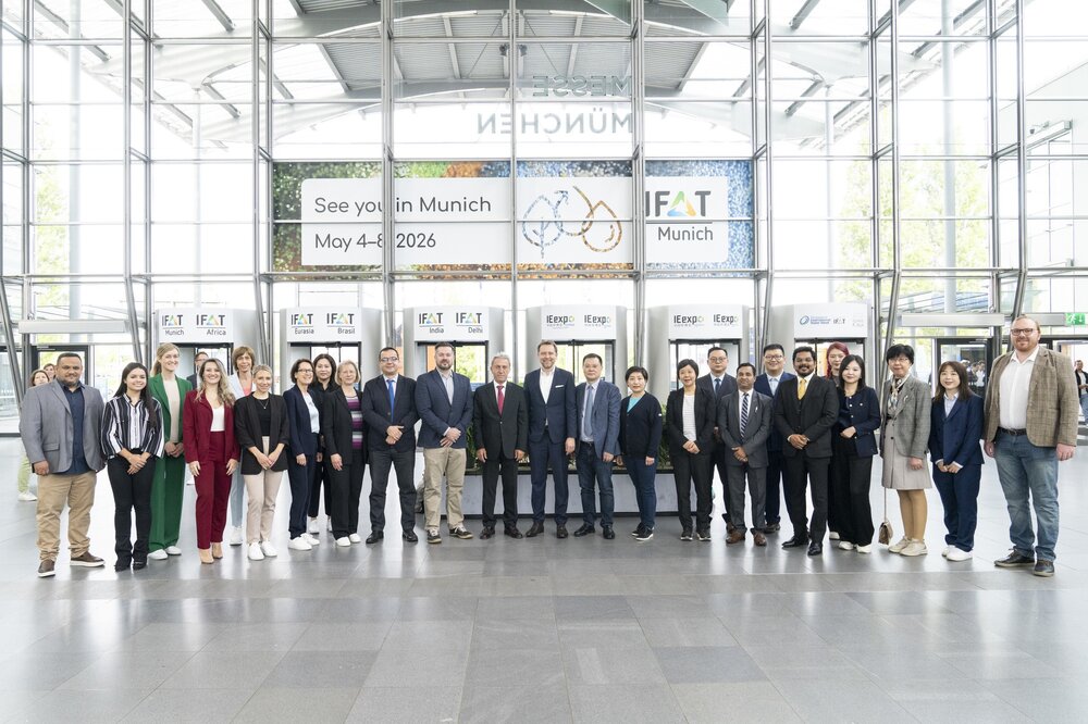The IFAT worldwide team poses in business attire in a row in the entrance hall of IFAT Munich.