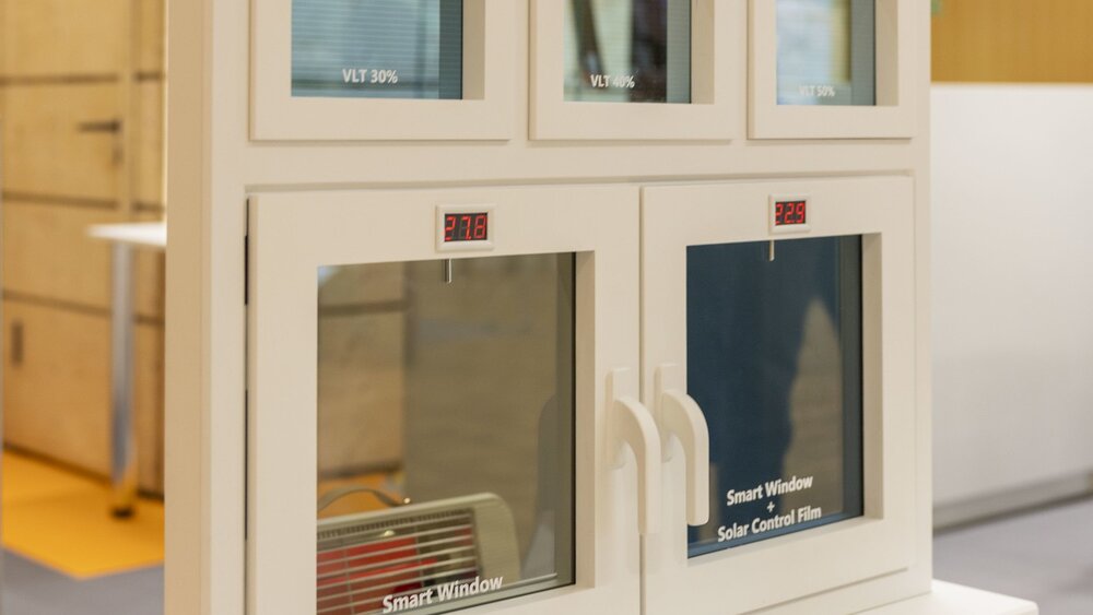 Ein Exponat, bestehend aus mehreren kleinen Fenstern auf einem Sockel, auf dem „Solar Smart Windows System“ steht.