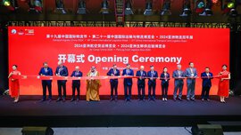 A group of people cut a red ribbon in front of a red background on stage at the opening ceremony of 