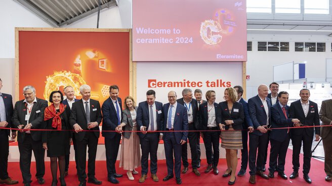 Eine Gruppe von Menschen in Anzügen steht auf der ceramitec talks Bühne hinter einem roten Band, das feierlich mit Scheren zerschnitten wird.